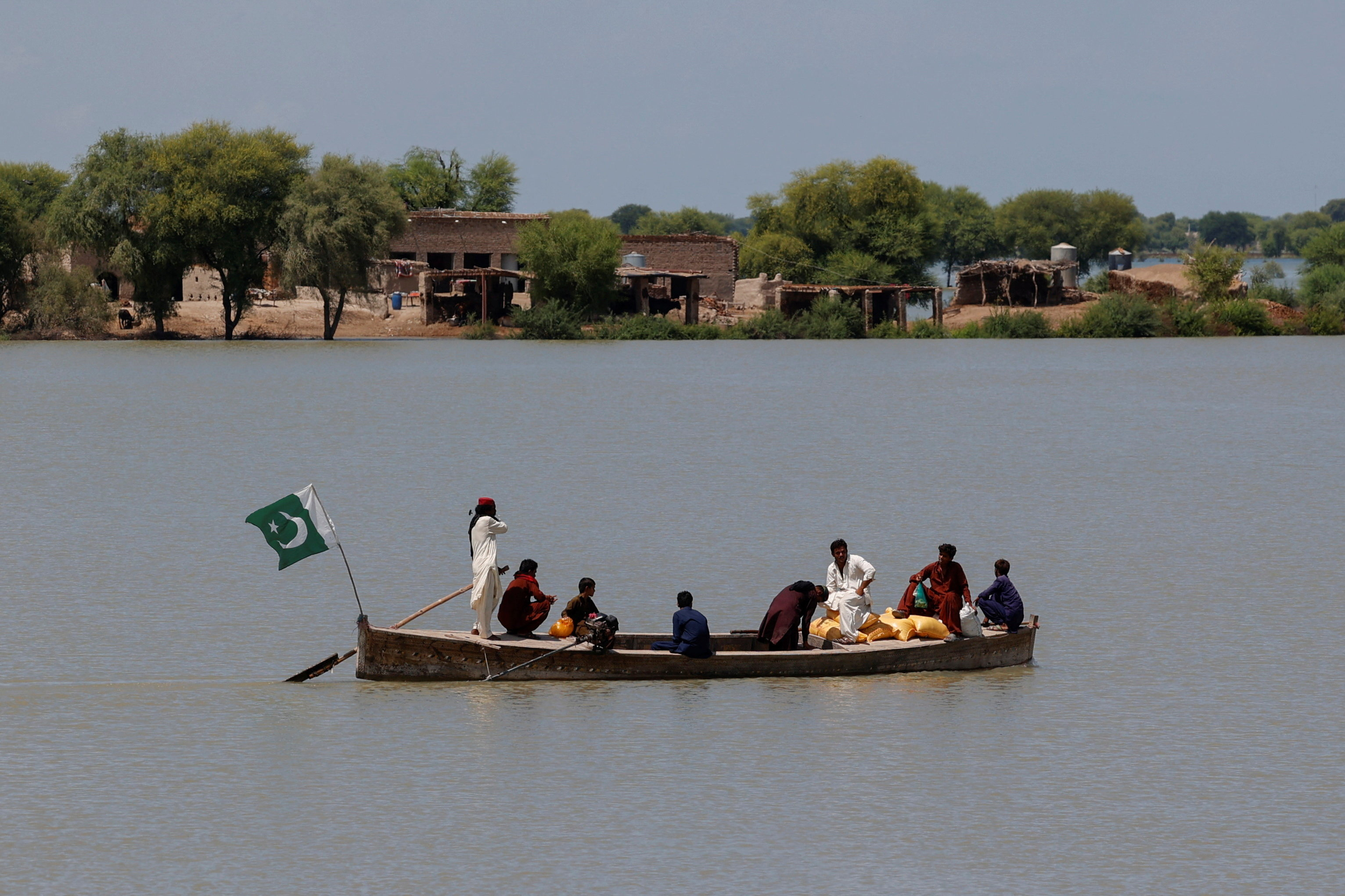 Residents travel on a boat with their supplies, through a flooded area, following monsoon rains and rising water levels of the Indus River, in Ghano Khan Jatoi village in Dadu district, Sindh province, Pakistan, September 12, 2025. REUTERS/Akhtar Soomro