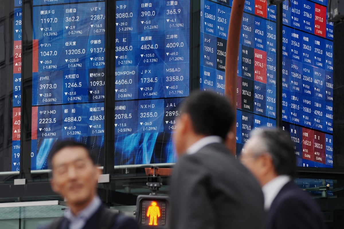 Pedestrians stand in front of an electronic quotation board displaying the Nikkei 225 stock prices on the Tokyo Stock Exchange during a morning session in Tokyo on November 18, 2025. (Photo by Kazuhiro NOGI / AFP)