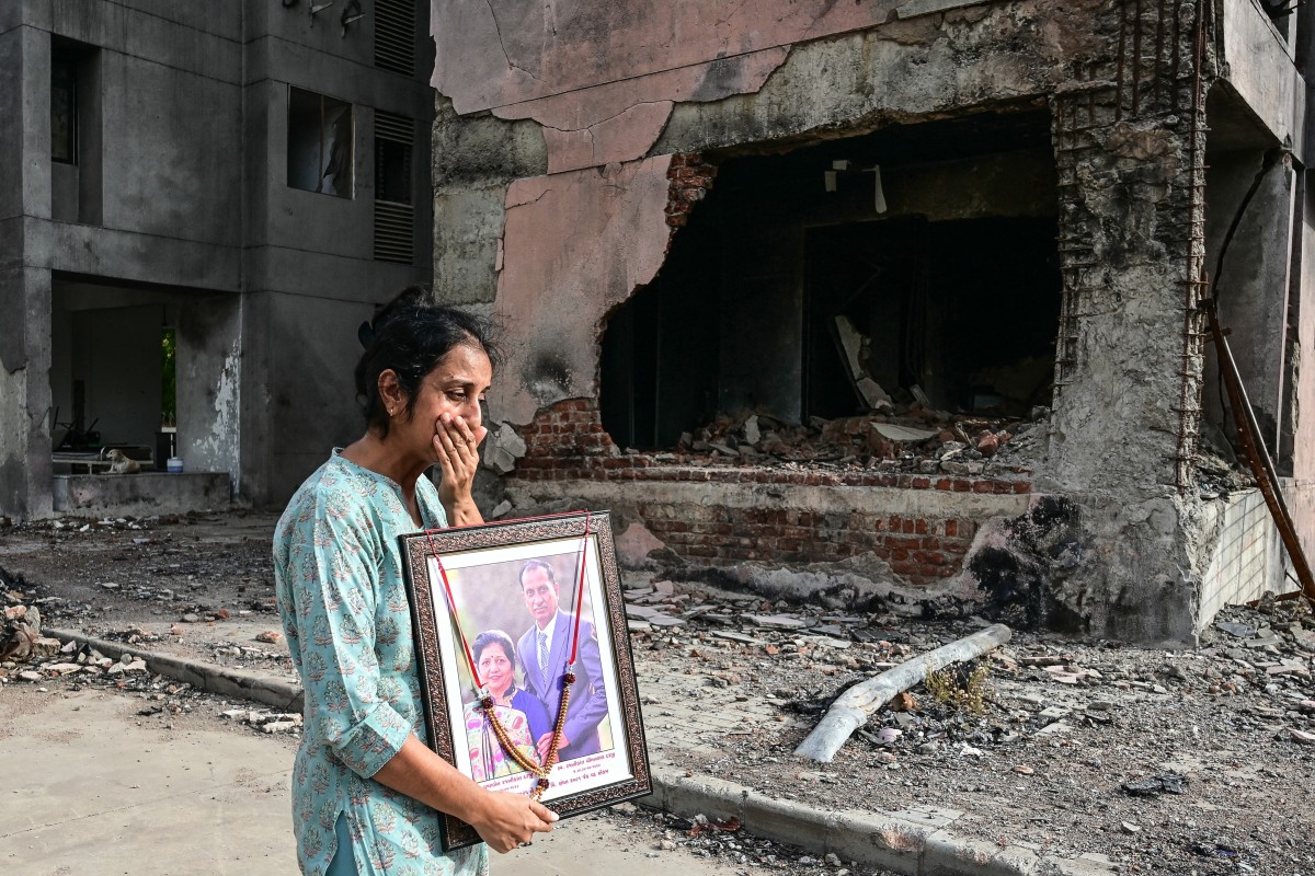 A woman holding a portrait of her relatives, who died in the Air India Flight 171 crash last year, breaks down while visiting the accident site in Ahmedabad on June 11, 2026. (AFP)