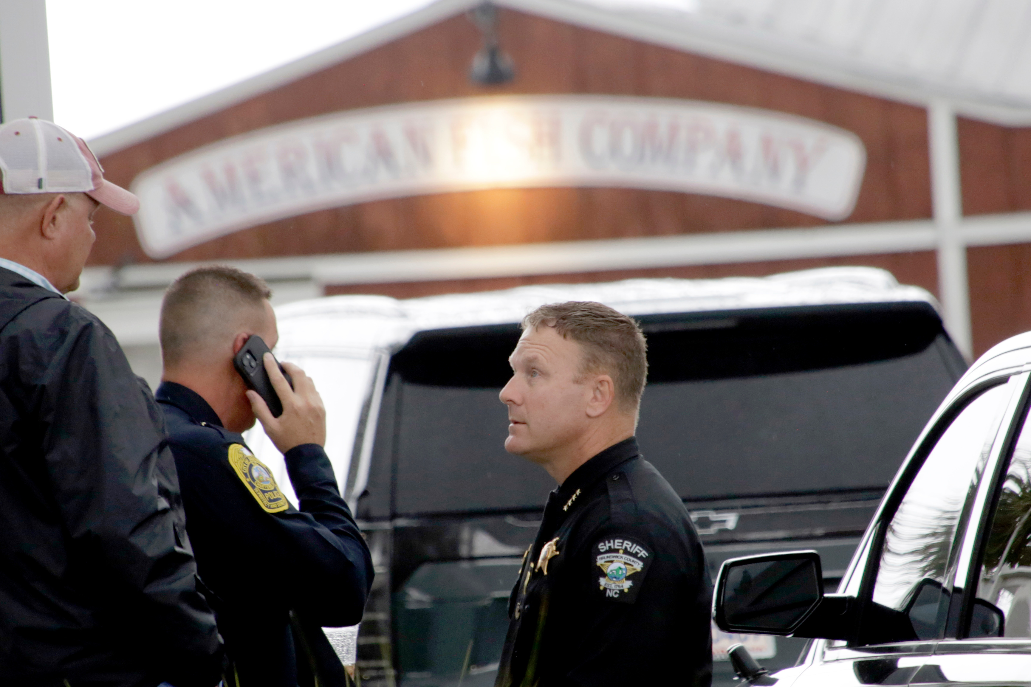 Police officers on the scene in front of the American Fish Company following a fatal shooting that occurred here the night before