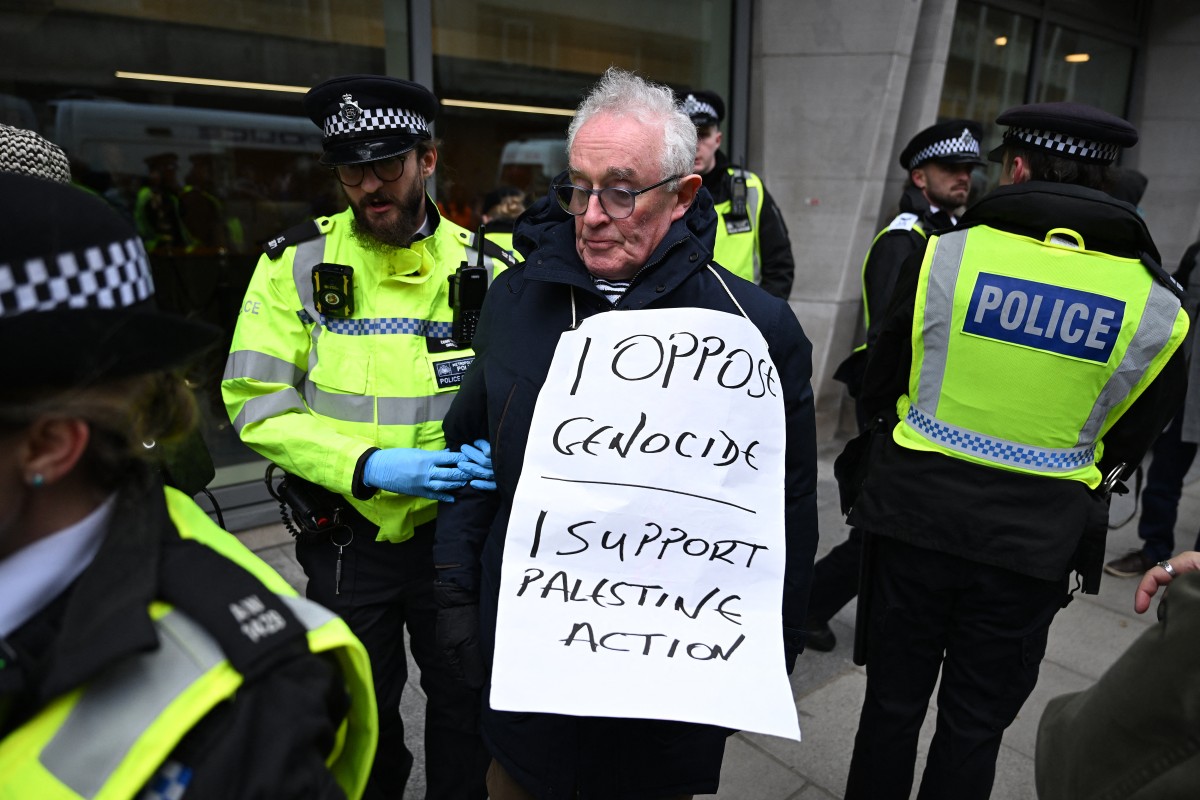 A protester is escorted away by police officers for taking part in a demonstration in support of "Defend Our Juries" and their campaign against the ban on Palestine Action, outside Britain's Ministry of Justice in London on November 20, 2025. (Photo by Ch