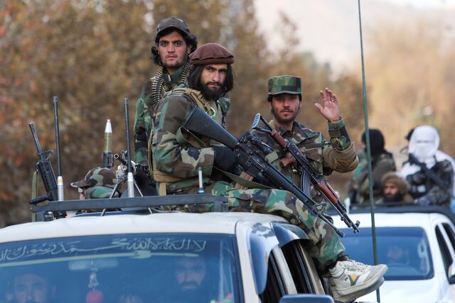 Taliban sit on a military vehicle