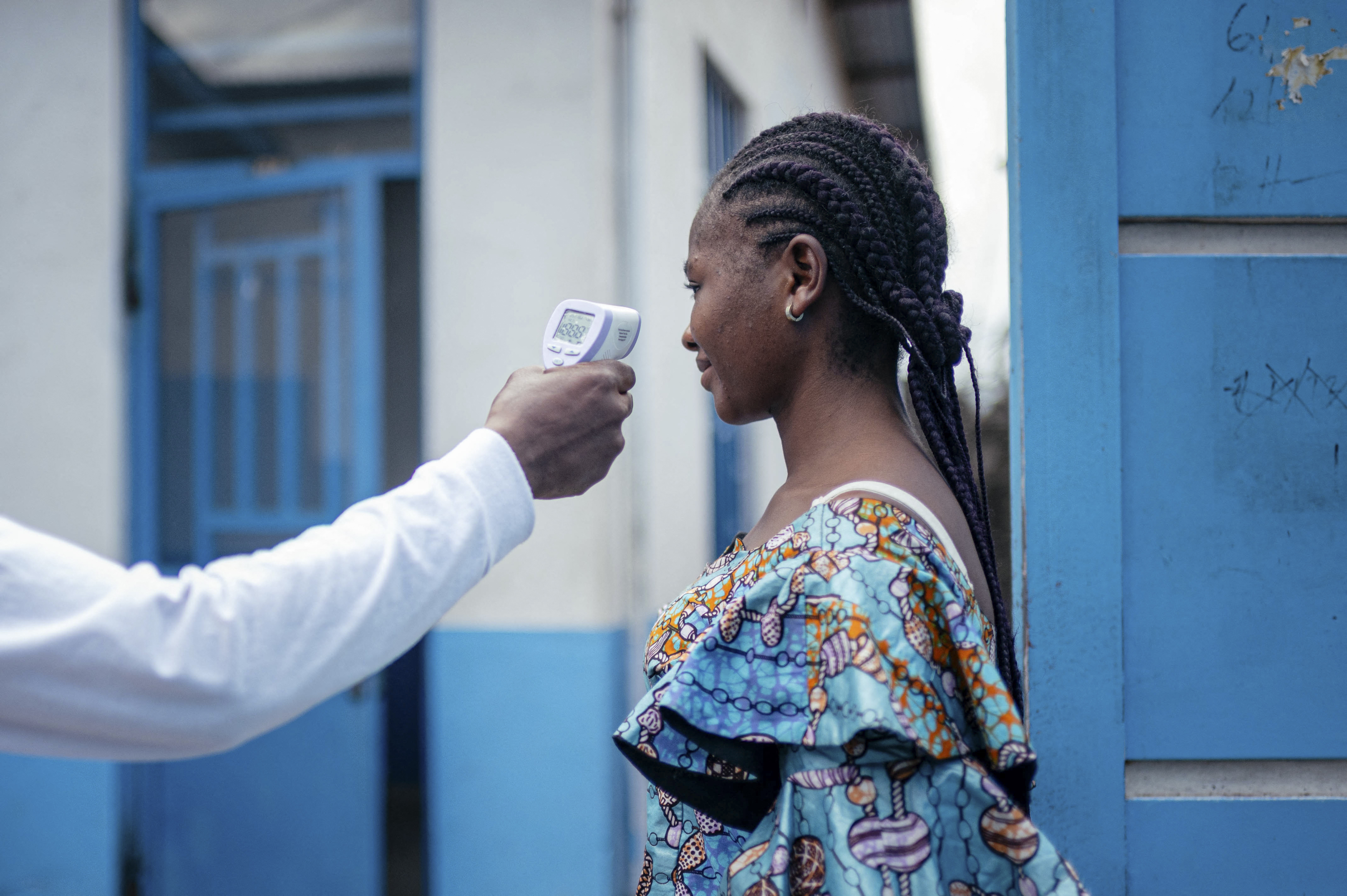 A staff member of the CBCA Virunga Hospital checks a visitor’s temperature using a a contactless infrared thermometer, before allowing her access to the hospital in Goma on May 17, 2026.