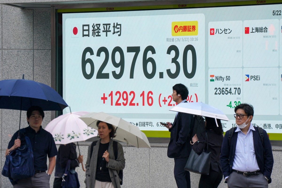 Pedestrians are pictured in front of an electronic quotation boards displaying the Nikkei Stock Average on the Tokyo Stock Exchange along a street in Tokyo on May 22, 2026. (Photo by Kazuhiro NOGI / AFP)