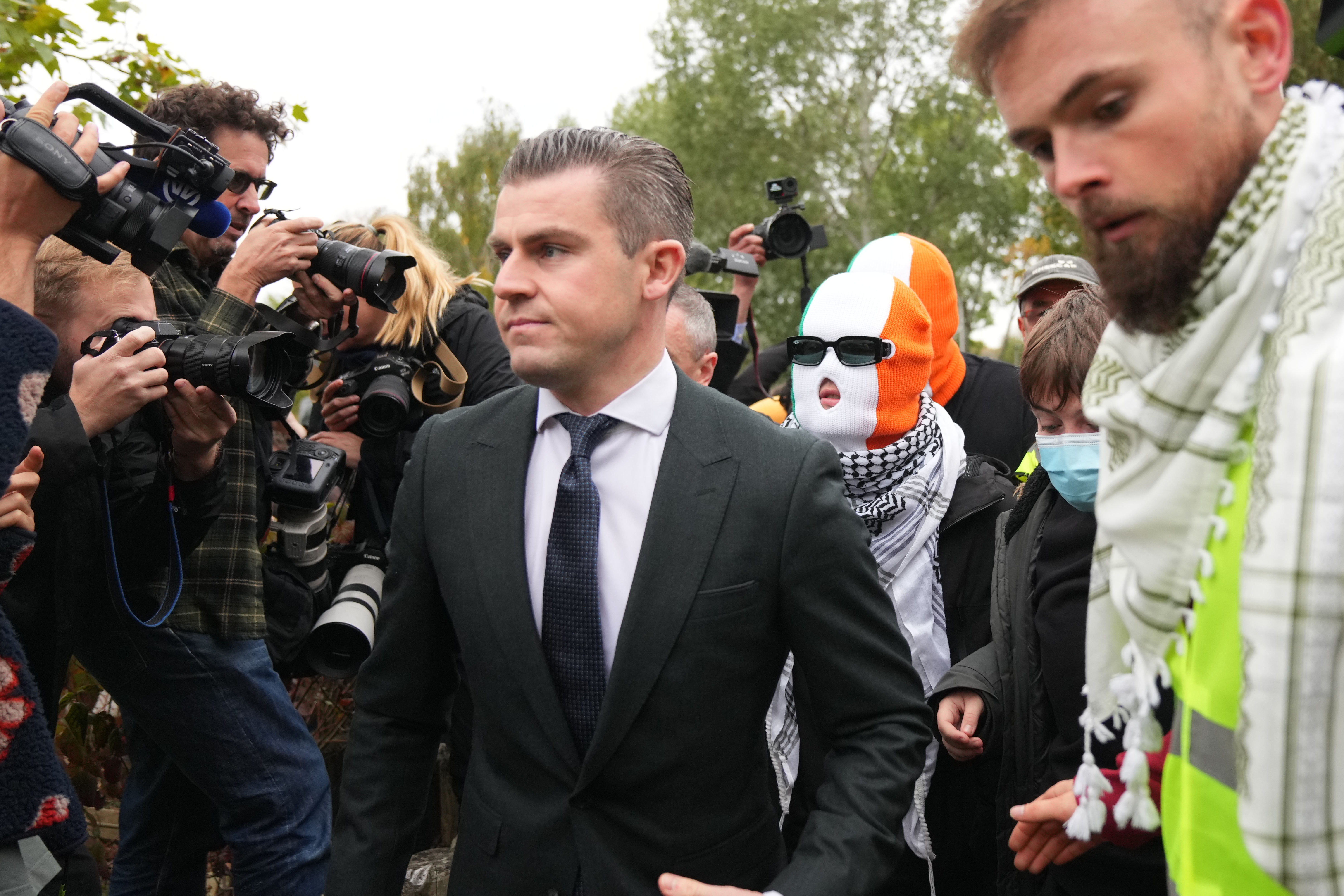  person believed to be Liam Óg Ó hAnnaidh, aka Mo Chara, in a mask, a member of the Irish language band Kneecap, arrives at Woolwich Crown Court in London, Friday