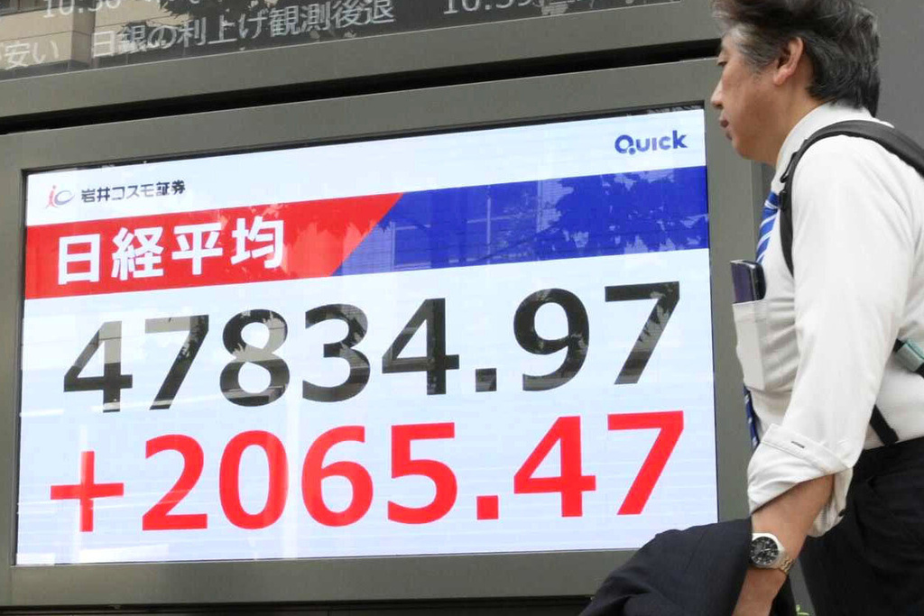 People walk by an electronic stock board showing Japan's Nikkei 225 index at a securities firm in Tokyo, Monday, Oct. 6, 2025. (Kyodo News via AP)